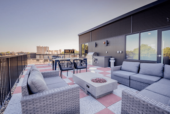 A patio with grey furniture and a fire pit.